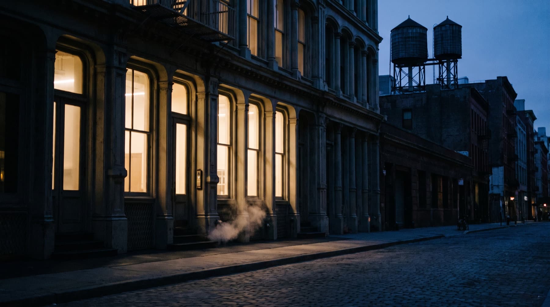 A cast-iron SoHo street in New York at blue hour with lit shopfronts